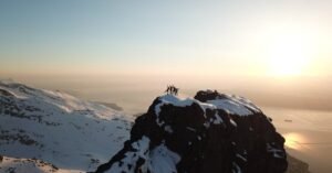 Adventurers celebrate atop a snow-covered peak in Narvik, Norway during sunrise.